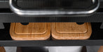 Two rectangular bamboo cutting boards with rounded corners and a black rubber grip, branded 'BLACK EARTH', displayed on a black carbon-fiber surface.
