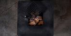 Top-down view of a black metal fireplace insert with a diamond-patterned lid and visible wood logs inside, set on a dark textured floor.